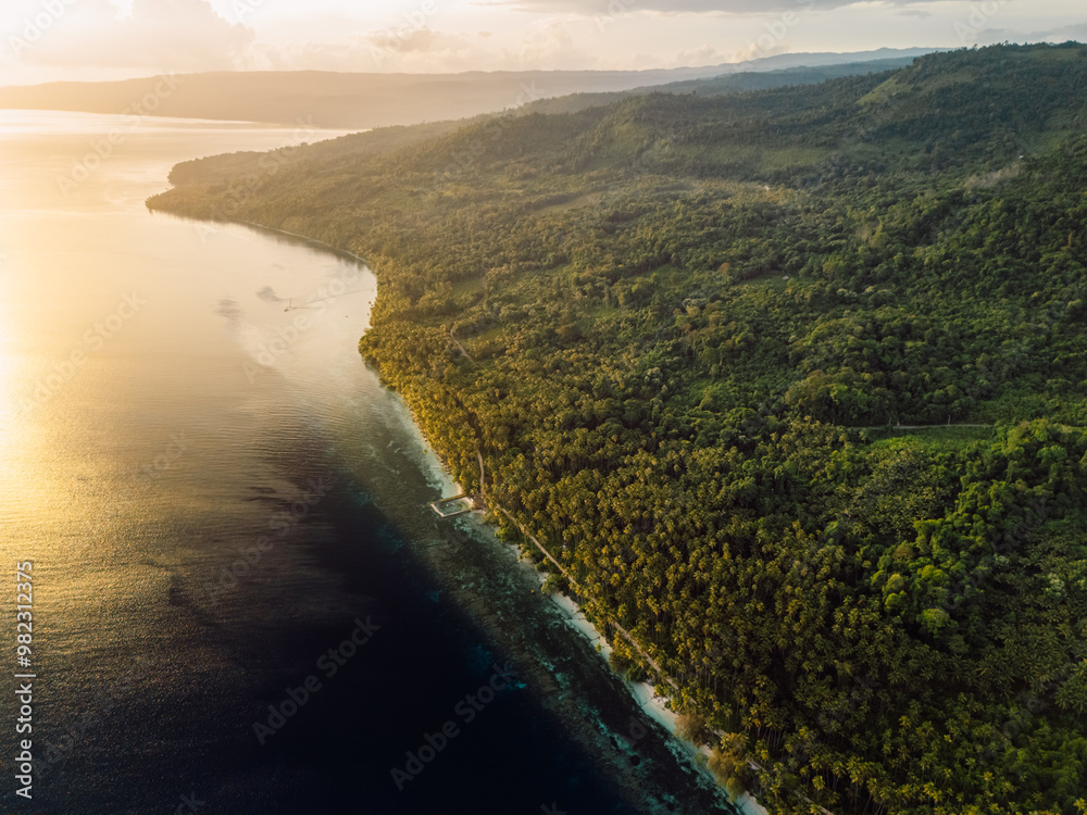 Coastline landscape with mountains and sunrise sunshine on scenic tropical island in Indonesia. Travel destination concept. Coastline landscape with mountains and sunrise sunshine on scenic tropical island in Indonesia. Travel destination concept.