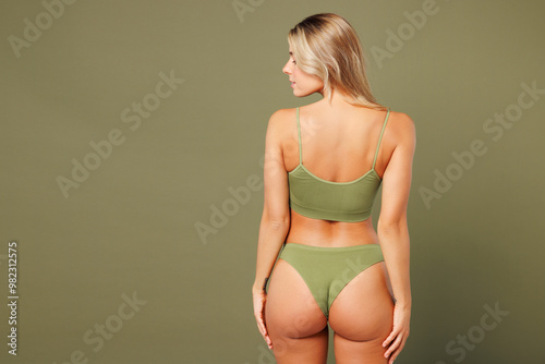 Tablou pe pânză Back rear view young nice lady woman with slim skinny body perfect skin wear top bra lingerie stand put hand on buttocks posing isolated on plain pastel green background