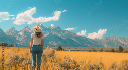 Ponoramic landscape with happy carefree woman enjoying freedom against autumn field meadow, mountain and sky cloud background. Holiday vacation and travel concept photo