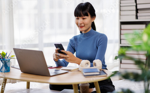 Smile asian woman working from home on laptop, freelance work online with phone and laptop documents 