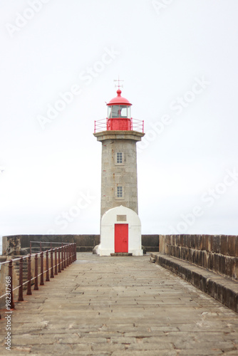 Red and white lighthouse on a pier with ocean view, vertical image