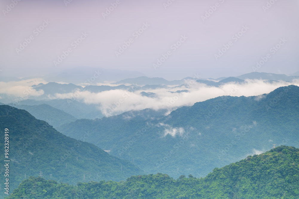 Obraz premium A serene mountain range is shrouded in a blanket of mist, creating a dreamy and ethereal atmosphere. The layers of hills and valleys stretch into the distance. Shizitou Mountain, Taiwan.