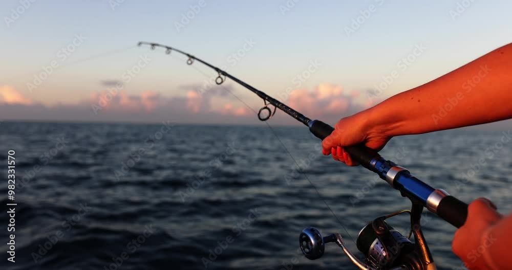 Woman holds spinning rod in hands and catches fish in sea. Tourist fishing