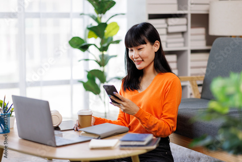 business woman talking with somebody while sitting at home and working on laptop. Happy business woman chatting on digital gadgets online, holding mobile phone, using laptop 