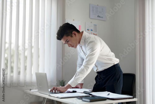 Serious young adult male working in office workplace