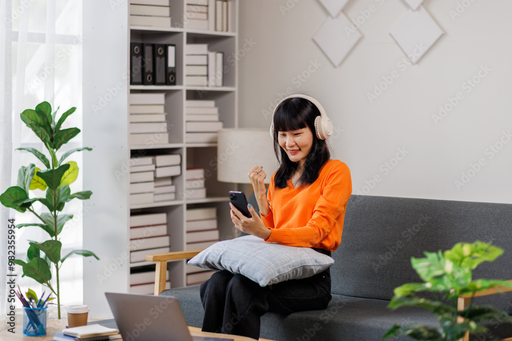 One caucasian woman asian female with headphones use mobile phone at home to listen to the music online happy smile sing joy have fun alone copy space