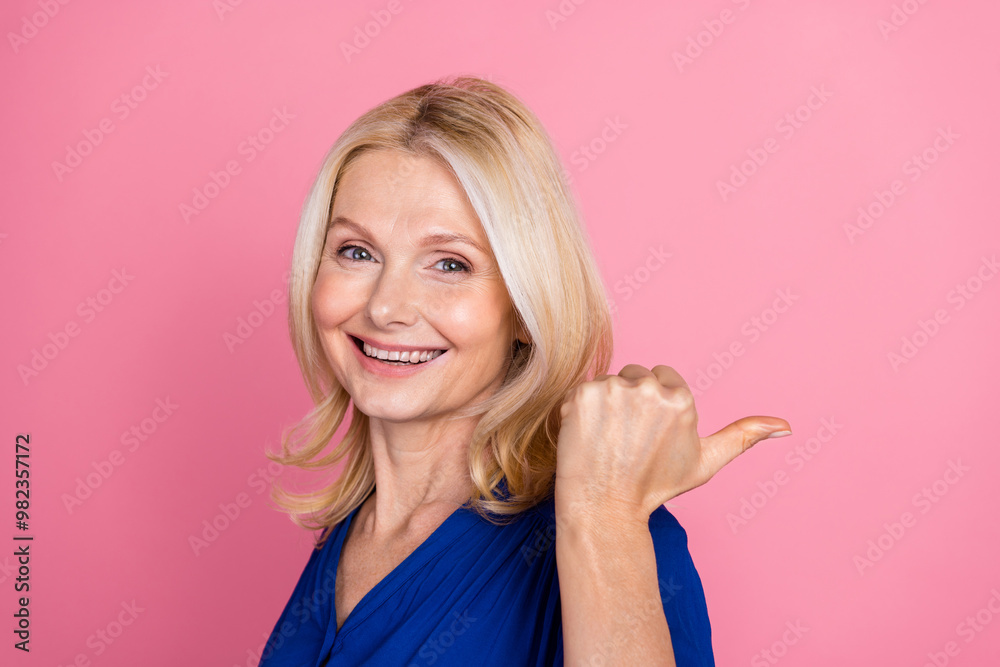 Photo portrait of pretty senior female point empty space wear trendy blue outfit isolated on pink color background Photo portrait of pretty senior female point empty space wear trendy blue outfit isolated on pink color background