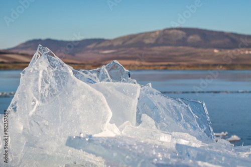 Winter landscape - detail of cracked crysta ice on the edge of the lake in the foreground and Pálava protected landscape area in the background, frosty sunrise in January, ice winter unique wonderland photo