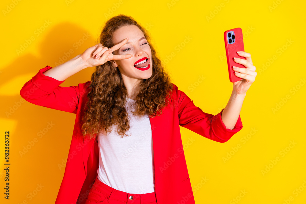 Naklejka premium Photo of pretty young woman selfie eye wink show tongue v-sign wear red suit isolated on yellow color background