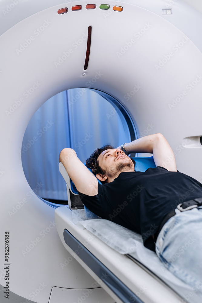 In a bright diagnostic center, a young man undergoes a CT or MRI scan ...