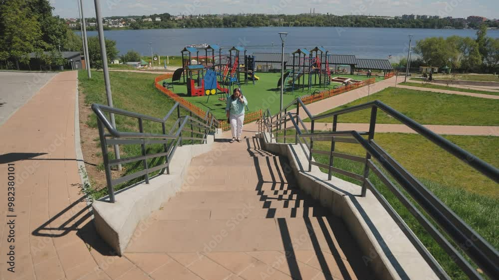 An attractive woman in a striped shirt and white pants is climbing the stairs in the park. Slow motion. Active lifestyle. An attractive woman in a striped shirt and white pants is climbing the stairs in the park. Slow motion. Active lifestyle.