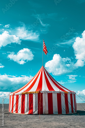 A large red and white striped circus tent with a flag on top photo