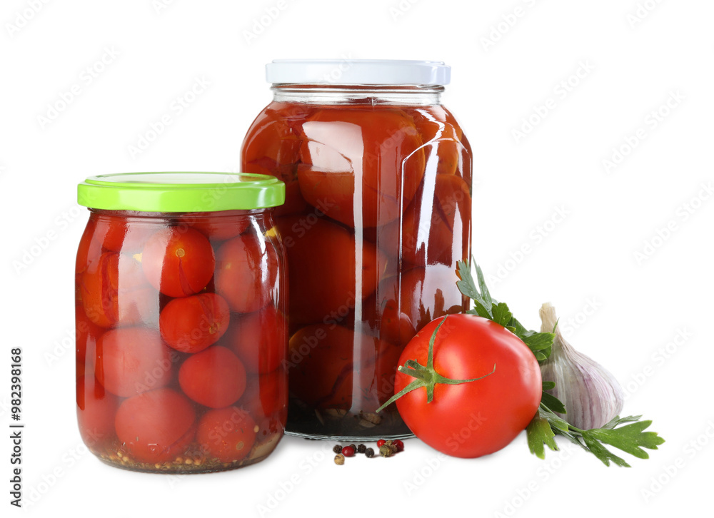 Tasty pickled tomatoes in jars, fresh vegetable and spices isolated on white