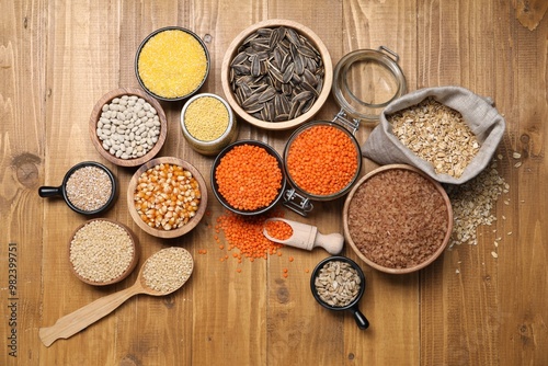 Different types of cereals, seeds and legumes on wooden table, flat lay