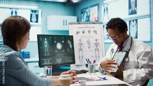 Wallpaper Mural African american specialist showing the human skeleton to explain diagnosis to patient, x ray imaging scan interpretation. Medical expert reviewing lab test results in cabinet. Camera B. Torontodigital.ca