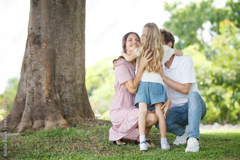 Fototapeta premium Happy family relaxing together at the park, caucasian family with father, mother, and children walking at the park.