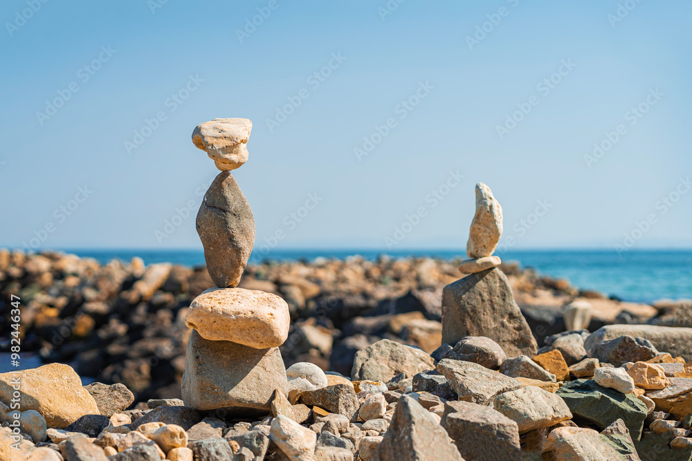 Two carefully balanced stone towers on rocky beach, harmony and balance in nature Two carefully balanced stone towers on rocky beach, harmony and balance in nature