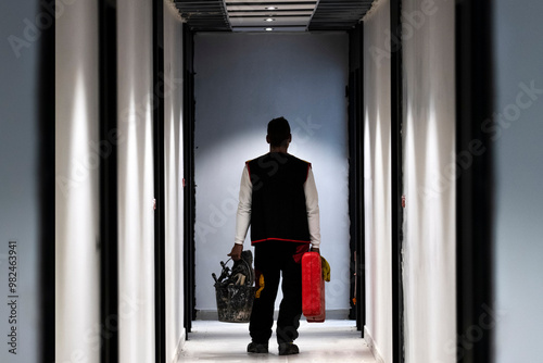 A dedicated Maintenance Worker in a hallway, equipped with essential tools to perform tasks