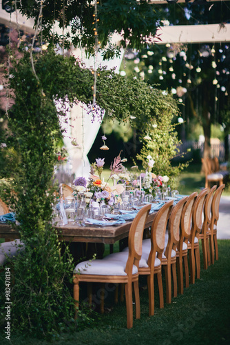 Obraz na płótnie Outdoor Wedding Reception with Brown Chairs and Decorated Tables on a Green Lawn in a Scenic Nature Setting w salonie