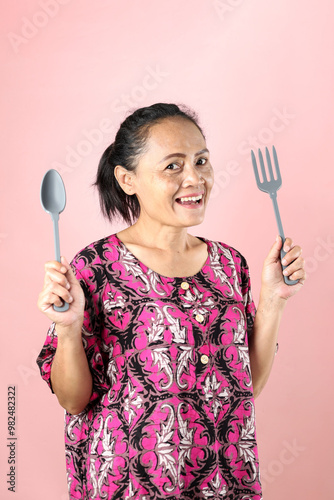 Indonesian Asian Middle Age Woman Holding SPoon and Fork,