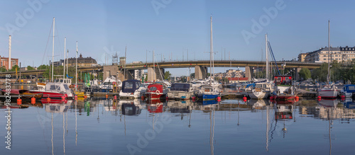 Panorama, the bay Årstaviken, a jetty with day curiser and sailing boats at the bridge Liljeholmsbron, sunny summer morning in Stockholm photo