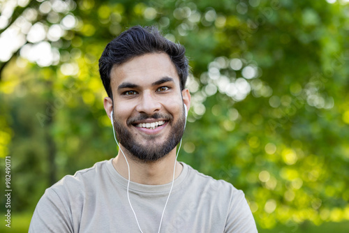 Smiling man with headphones enjoying music in outdoor park setting