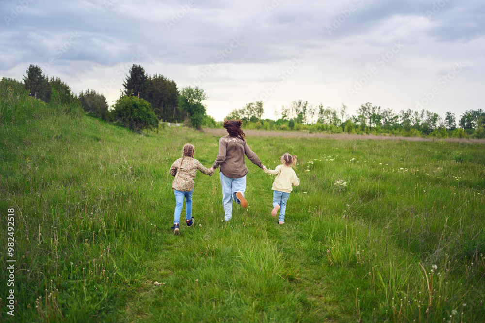 mother and children run holding hands in the field mother and children run holding hands in the field