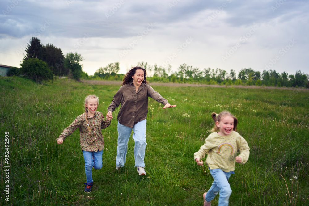 mother and children run holding hands in the field mother and children run holding hands in the field