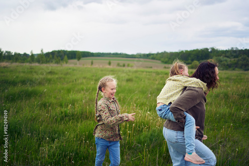 a mother rolls her daughters on her back, playing horse, kisses and hugs