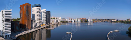 Train bridge view at the bay Årstaviken, apartment skyscrapers reflecting and a tug boat passing bridge, a tranquil early sunny spring day in Stockholm