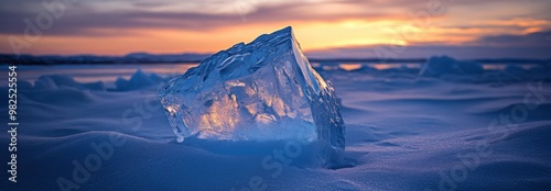 A large icey blue diamond melting in the sunset on an arctic beach, surrounded by snow and icy sand dunes. photo