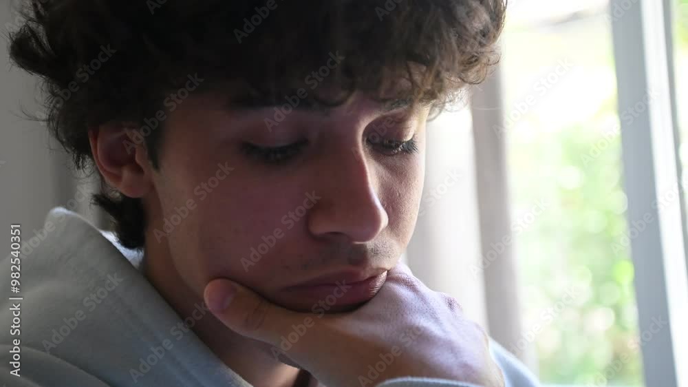 Plano fechado de jovem adulto pensativo na bancada de estudos, fazendo tarefa universitária