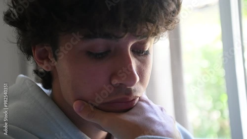 Plano fechado de jovem adulto pensativo na bancada de estudos, fazendo tarefa universitária