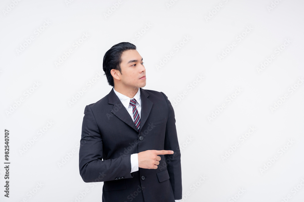 A serious young asian business executive in a fashionable suit and tie pointing to his right. Isolated on a white background. A serious young asian business executive in a fashionable suit and tie pointing to his right. Isolated on a white background.