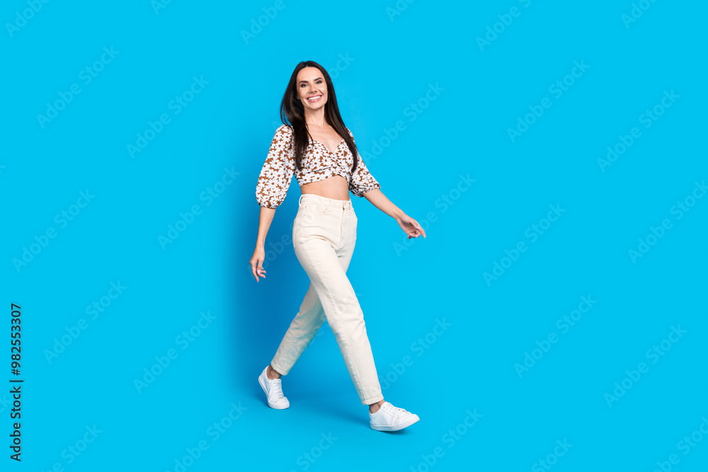 Photo of stunning lovely woman wear trendy clothes go empty space isolated on blue color background Photo of stunning lovely woman wear trendy clothes go empty space isolated on blue color background