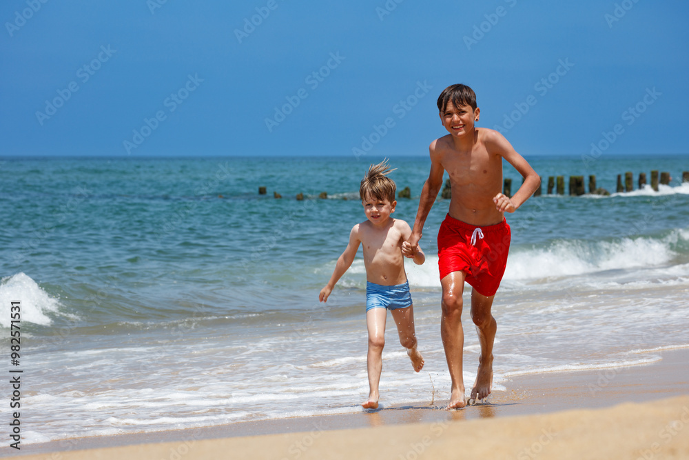 Brothers running alongside each other on the beach have fun Brothers running alongside each other on the beach have fun