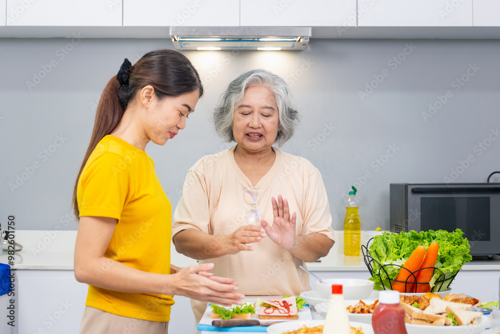 Senior asian mother and middle aged daughter cooking together at kitchen Senior asian mother and middle aged daughter cooking together at kitchen
