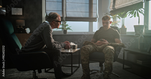 Senior psychiatrist talks to patient, gives antidepressants or sedative medicines to military man with PTSD. Psychotherapist conducts psychological therapy or post war rehabilitation for soldier.