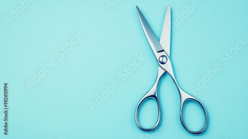 A shiny pair of scissors on a pastel blue background.