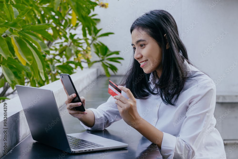Young asian woman holding credit card and using laptop computer. Online shopping concept. Young asian woman holding credit card and using laptop computer. Online shopping concept.