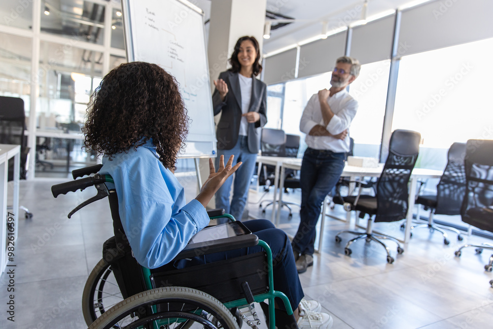 Executive woman with disability in wheelchair in office giving presentation on strategy Executive woman with disability in wheelchair in office giving presentation on strategy