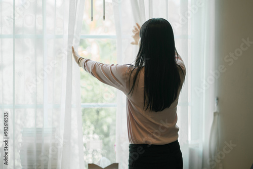 Woman stands in front of a window with a white curtain.Scene is calm and peaceful, as the woman is standing still and looking out the window. Free Download Woman stands in front of a window with a white curtain.Scene is calm and peaceful, as the woman is standing still and looking out the window. - GFXLoad