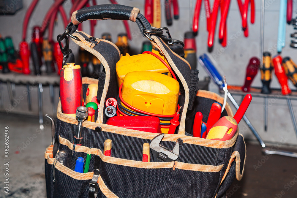 An electrician's bag full of tools stands in the workshop. An electrician's bag full of tools stands in the workshop.