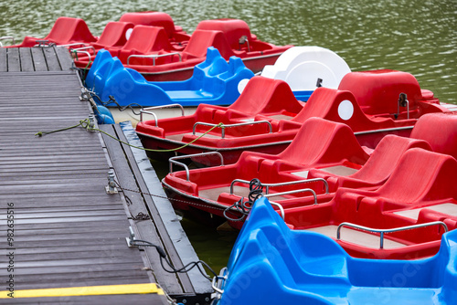 Obraz na płótnie Red and blue pedalo parked on the pond next to the wooden jetty. Water recreation equipment ready for action w salonie