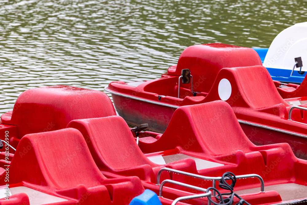 Red and blue pedalo parked on the pond next to the wooden jetty. Water recreation equipment ready for action