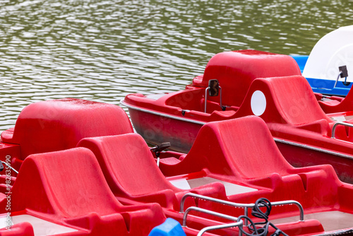 Obraz na płótnie Red and blue pedalo parked on the pond next to the wooden jetty. Water recreation equipment ready for action w salonie