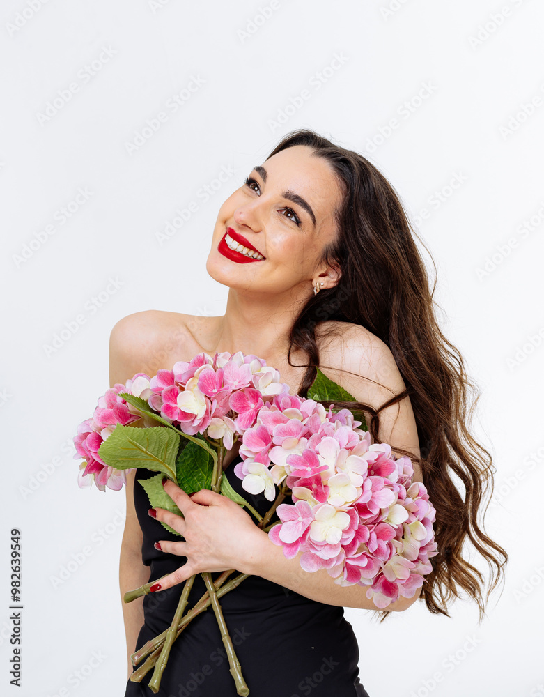 Joyful woman holding vibrant pink flowers indoors. A woman with long hair, smiling brightly while embracing a bouquet of pink flowers Joyful woman holding vibrant pink flowers indoors. A woman with long hair, smiling brightly while embracing a bouquet of pink flowers
