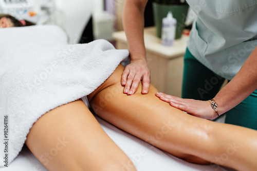 Beautiful young adult brunette receiving professional relaxation massage treatment at beauty spa salon.