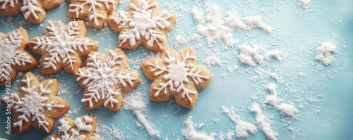 Delicious snowflake-shaped cookies decorated with white icing on a light blue surface, perfect for winter celebrations.