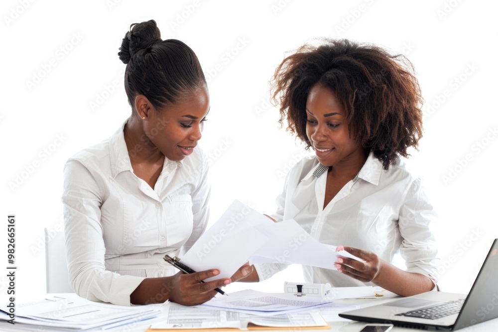 Two females reviewing papers and discussing something at a table Two females reviewing papers and discussing something at a table